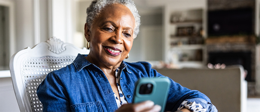 Smiling woman sitting in a living room chair, looking at her phone